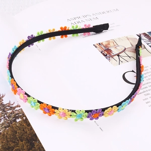 Detail of a thin black headband featuring colorful embroidered daisy flowers on a magazine
