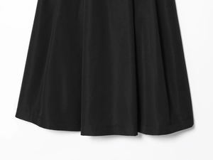 Dettaglio dell'orlo plissettato in denim con cuciture precise e drappeggio in tessuto nero