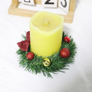 Detail of a mini Christmas wreath featuring a yellow LED candle and red plaid ribbon