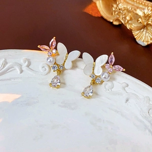 Détails macro des boucles papillon avec perles, zircon rose et goutte de cristal