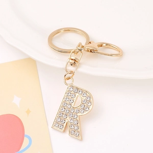 Close-up of golden metal letter R keychain with sparkling rhinestones and lobster clasp