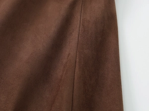 Texture macro détaillée du tissu en daim marron montrant les coutures et la matière velours