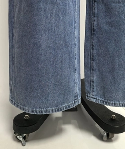 Close-up of neat flat-stitched hems on vintage washed wide-leg blue denim jeans