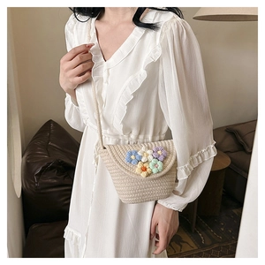 Detail of hand-woven straw bucket bag featuring colorful crochet flowers and braided strap