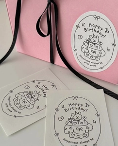 Detail of pink gift bags with oval Happy Birthday stickers featuring rabbit cake illustration