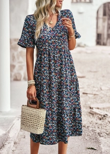 Deep blue V-neck short sleeve floral midi dress styled with a woven straw bag outdoors