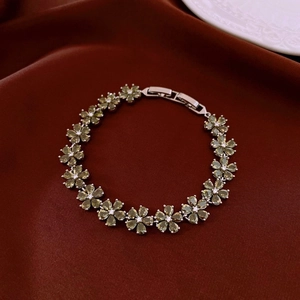 Détail d'un bracelet floral en zircon vert olive posé sur un fond en soie rouge foncé