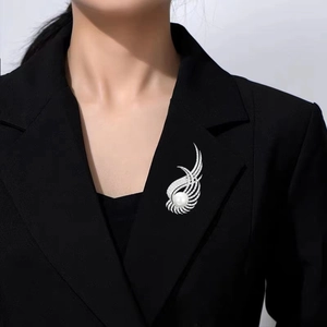 Vue détaillée d'une broche aile en argent avec zircons et perle sur revers de veste