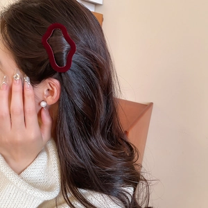Close-up of deep red flocked wavy hair clip with velvet texture on model's hair