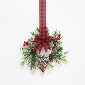 Close-up of artificial pine needles, red berries, and cones on the Christmas wreath