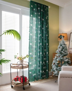 Detail of dark green Christmas curtain with white snowflakes and green fringe tassels
