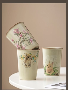 Detail of Ru Kiln ceramic mugs featuring hand-painted cats, rabbits, and floral motifs