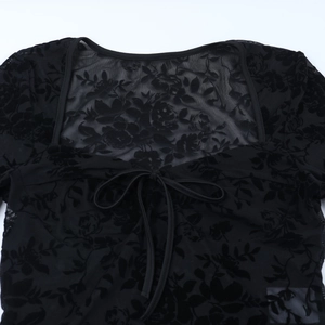 Vue détaillée d'un haut en dentelle noire avec motif de roses floquées et laçage frontal