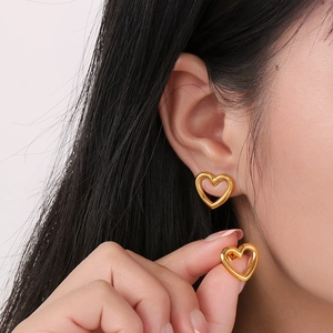 Détail du mannequin portant des boucles d'oreilles cœur en or évidé avec diamants brillants