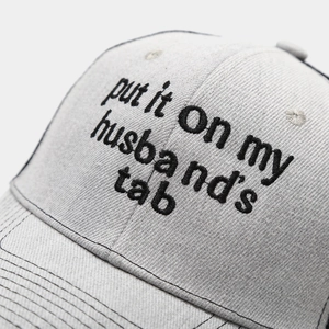 Detail of high-quality black embroidery on a light gray cotton trucker baseball cap