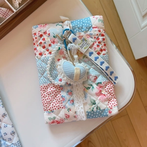 Detail of floral quilted cotton pouch with pearl chain and heart lace pendant charm