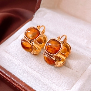 Close-up of vintage amber resin square pendant earrings on a soft cream jewelry display