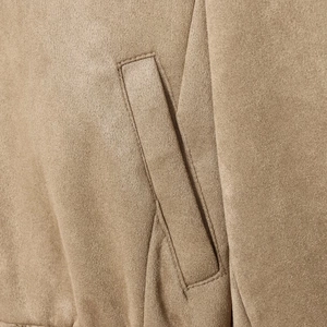 Gros plan d'une veste en daim camel montrant les détails de la poche et la couture