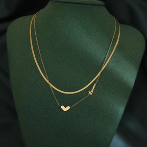 Détail du collier double rang doré avec chaîne serpent et pendentif en forme de cœur