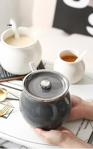 Detail of dark gray ceramic seasoning jar with lid and white ceramic spoon for spices