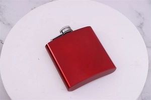 Close-up of a red stainless steel 6oz hip flask with a silver screw cap on marble