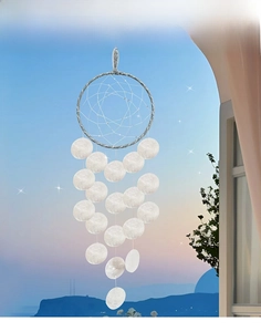 Detail of dreamcatcher wind chime with silver ring and shell pendants on window background