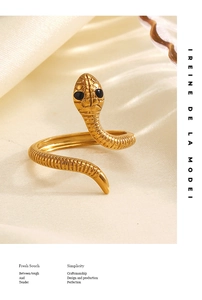 Dettaglio di un anello a serpente dorato con occhi di perle nere e trama a scaglie