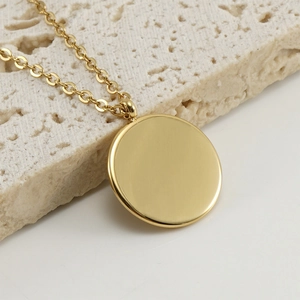 Polished stainless steel gold necklace with a round turquoise pendant on a stone base