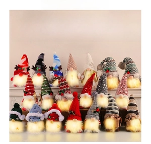 Close-up of assorted glowing Christmas gnome dolls with sequined hats and LED lights