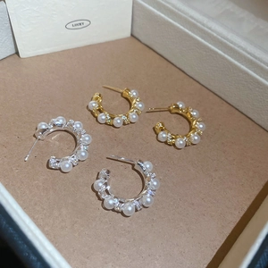 Detailed close-up of gold and silver C-shaped pearl and zircon stud earring sets
