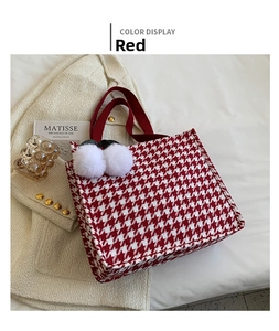 Detail of red houndstooth tote bag featuring plush charms and woven fabric texture