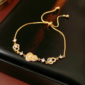 Detailed close-up of 18k gold plated bracelet with cat eye stone and heart charms on black leather