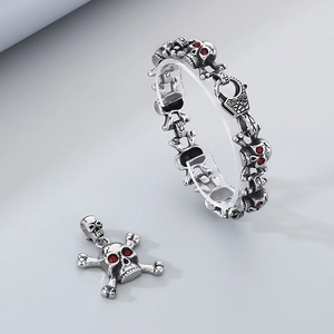 Detail of skull jewelry set with red gemstone eyes and polished stainless steel finish