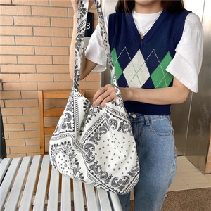 Detailed view of paisley canvas tote bag with wide shoulder strap worn by a model