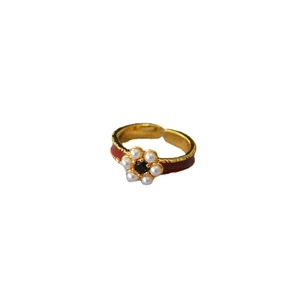 Elegant gold brass ring with red enamel and pearl flower centerpiece in a clean studio shot