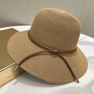 Détail de la texture tissée du chapeau de paille kaki orné d'un cordon en cuir marron