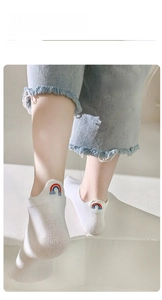 Close-up of white cotton ankle socks featuring cute rainbow embroidery on the heel tab