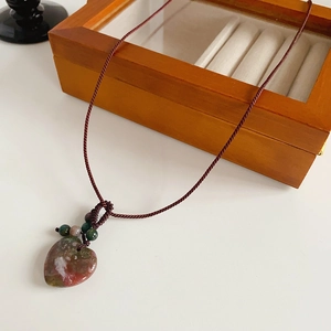 Detail of a vintage heart pendant made of red stone on a brown woven rope cord