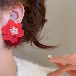Close-up of red frosted flower earring with a plush pom-pom and crystal center