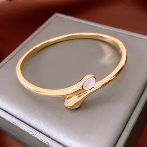 Minimalist gold-plated oval bypass bangle with a polished finish and mother-of-pearl stone