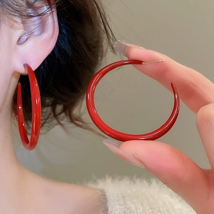 Close-up of elegant red enamel round hoop earrings with glossy finish and silver pins
