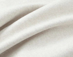 Macro view of soft beige wool fabric texture showing detailed fibers and fold draping