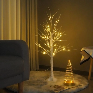 Close-up of warm white LED birch tree and golden spiral Christmas tree lights on a rug