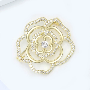 Close-up of golden hollow camellia brooch with micro-pave zircons and floral details