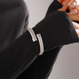 Detail of silver stainless steel snake-shaped spiral bracelet on model's wrist