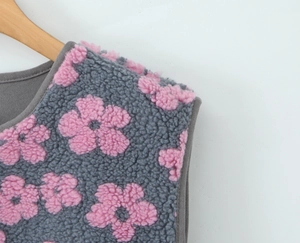 Detail of grey fleece vest featuring pink floral patterns and high-quality stitching