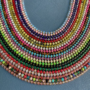 Colorful handmade natural stone beaded necklaces with gold accents layered on blue leather