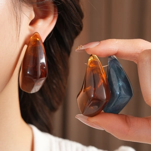 Macro shot of large amber and blue teardrop resin earrings with vintage textures
