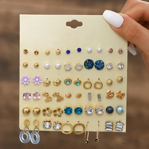 Close-up of 30 pairs earring set featuring gold bows, faux pearls and colorful crystals