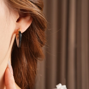 Close-up of heart-shaped gold-plated zircon earrings worn by a model in soft lighting